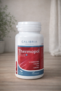 Bote de Thermopol Plus Calibria con 60 cápsulas vegetales sobre fondo neutro de madera.